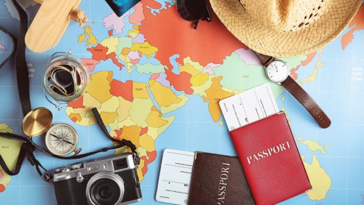 Imagem com elementos relacionados a viagem, como passaporte, chapéu, relógio, máquina fotográfica etc.