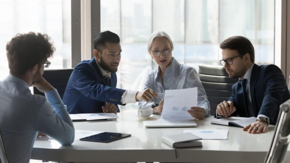Empresários reunidos na sala de reuniões discutindo estatísticas financeiras da empresa