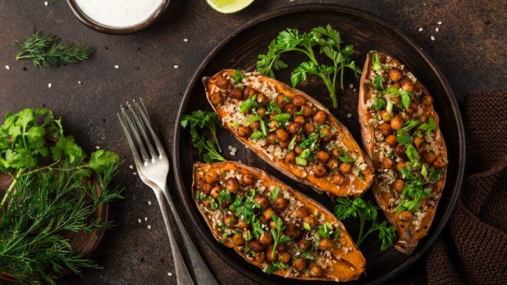Três partes de batata-doce recheadas com grão-de-bico e quinoa em prato preto com salsinha