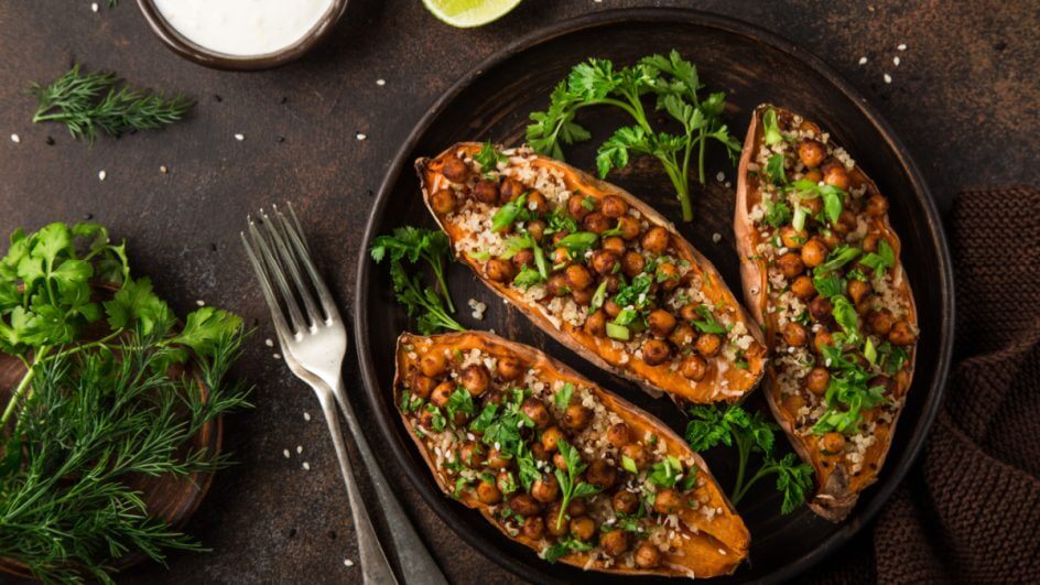 Três partes de batata-doce recheadas com grão-de-bico e quinoa em prato preto com salsinha