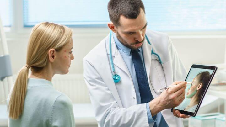 Médico mostrando imagem em tablet de rosto para a paciente