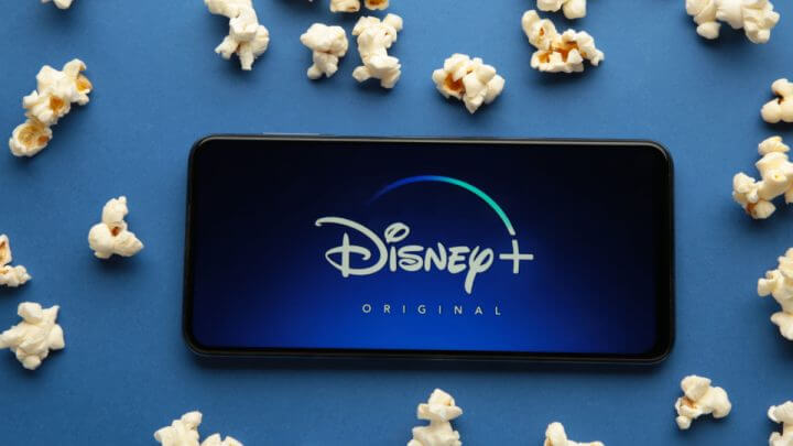 Smartphone com abertura do Disney+ ao redor de pipocas