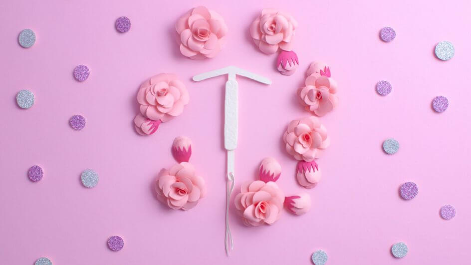 Desenho de DIU ao redor de flores, em fundo rosa