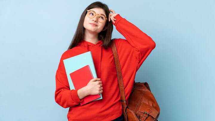 Mulher vestindo blusa vermelha e usando óculos olhando para o alto e com a mão na cabeça