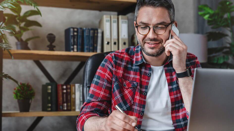 Homem sentado sorrindo falando no telefone