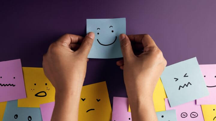 Post-its de diferentes cores colados em parede roxa simulando emoções