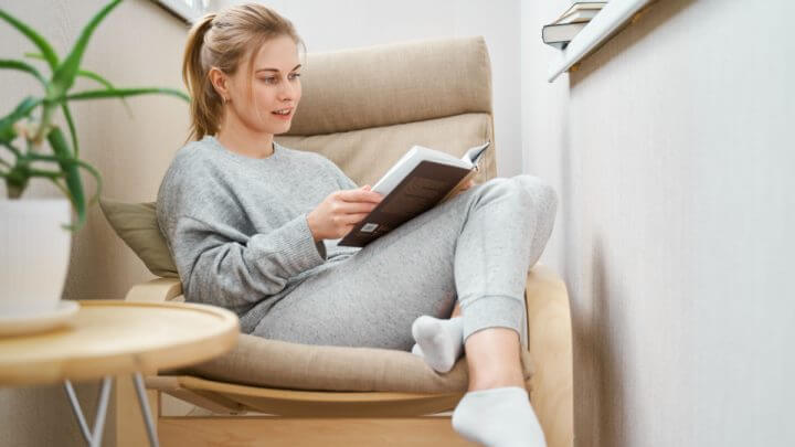 Mulher sentada em poltrona lendo livro