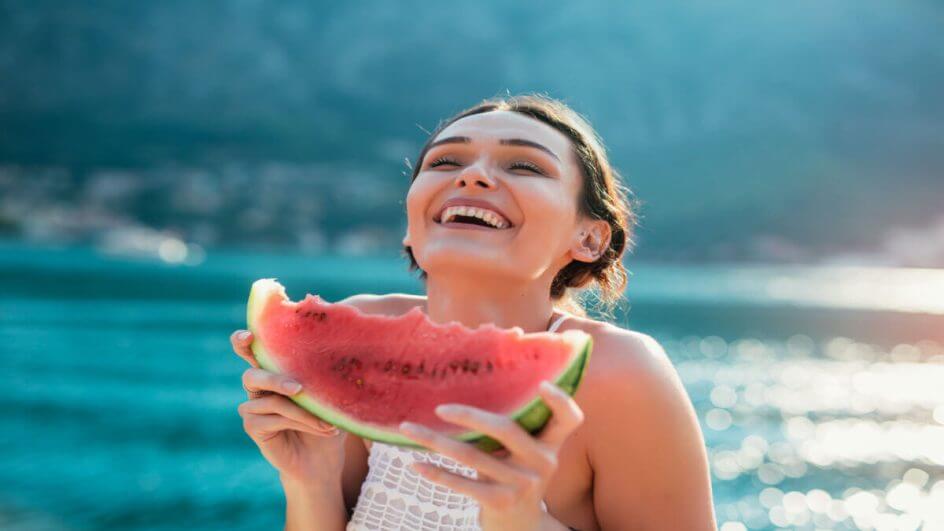 Mulher sorrindo comendo melancia