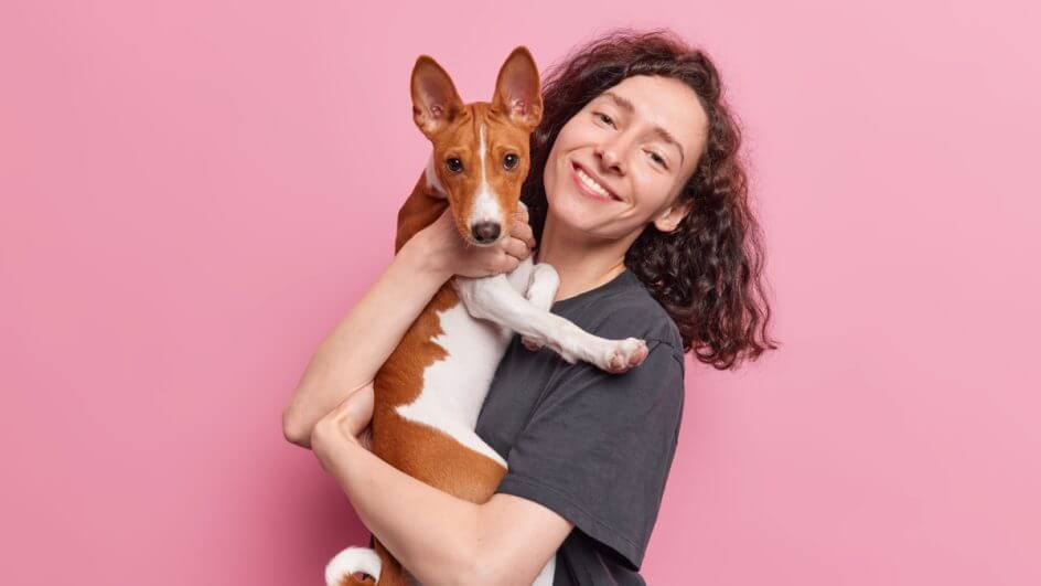 Mulher sorrindo e abraçada com cão