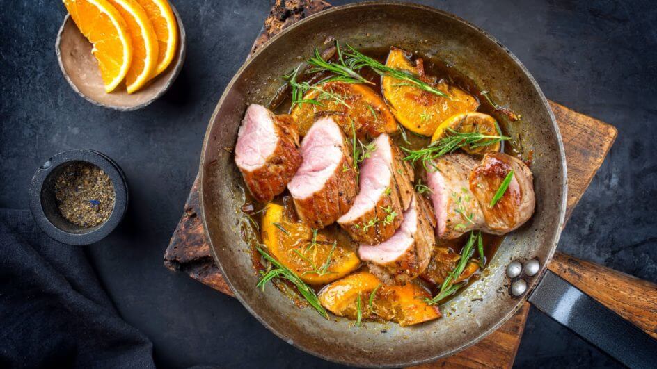 Carne assada em panela com molho, alecrim e fatias de laranja