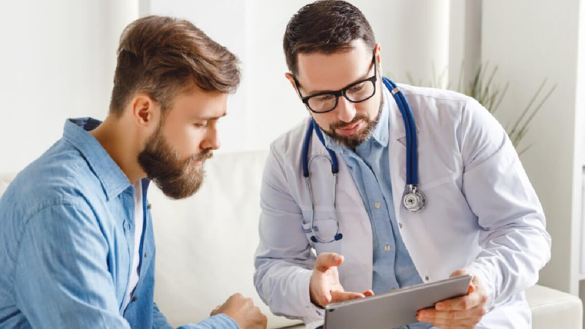 Homem e médico sentados conversando e olhando para a tela de um tablet
