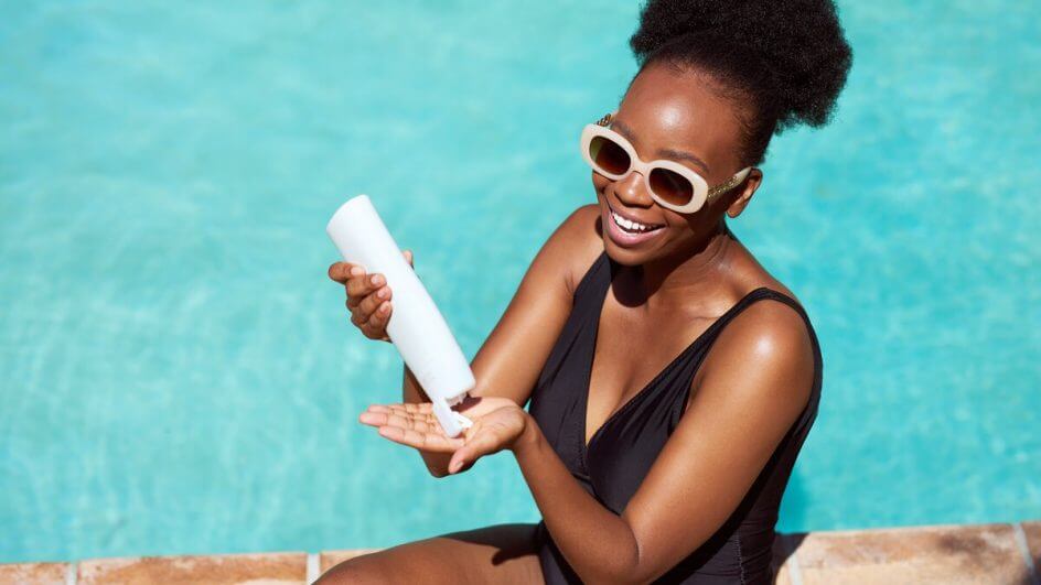 Mulher passando protetor solar na beira de uma piscina