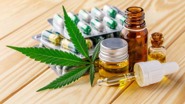 Comprimidos e remédios em óleo. Folha de maconha à frente