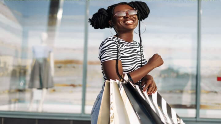 Mulher negra sorrindo com sacolas no braço