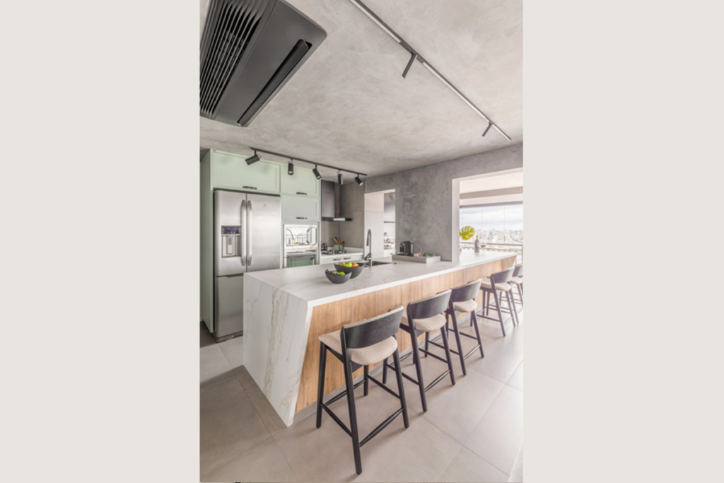 Na bancada que come&ccedil;a na cozinha e se estende at&eacute; a varanda gourmet, o arquiteto&nbsp;investiu na naturalidade do porcelanato (Projeto: BMA Studio | Foto: Guilherme Pucci)