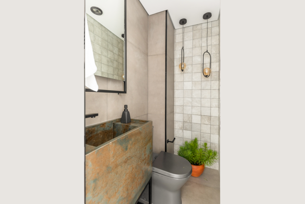 Neste lavabo, o apelo r&uacute;stico do a&ccedil;o corten marca presen&ccedil;a na bancada com cuba esculpida com porcelanato (Projeto: BMA Studio | Foto: Guilherme Pucci)