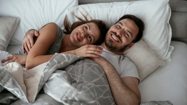 Mulher e homem sorrindo deitados em uma cama