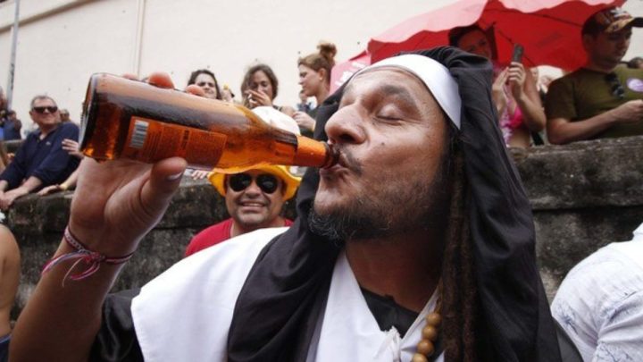 Homem de meia idade fantasiado e tomando uma garrafa de cerveja