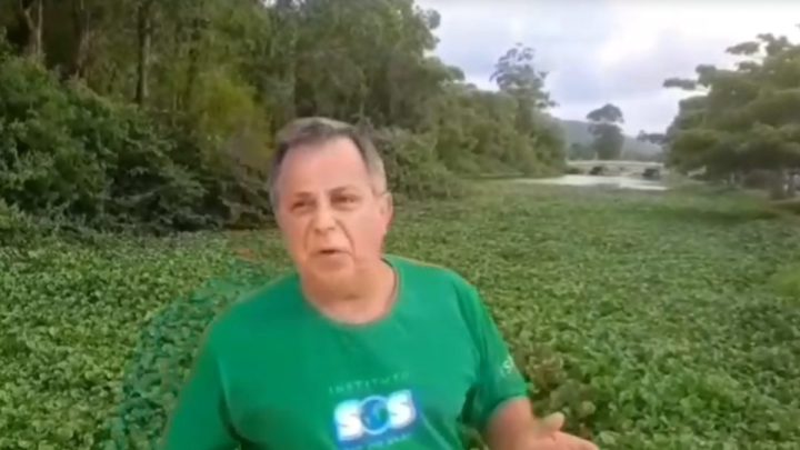 Homem em frente ao rio cheio de plantas em cima da água