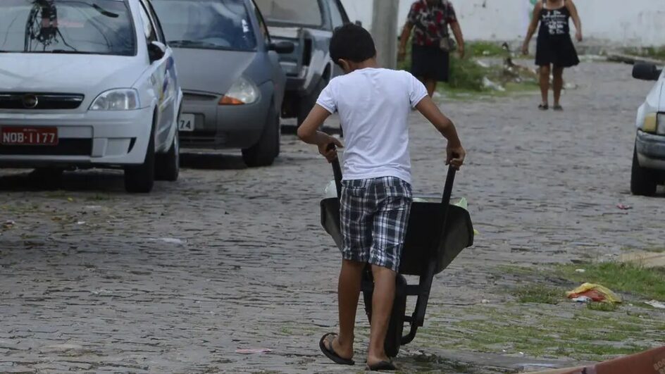 Criança carrega carrinho de mão
