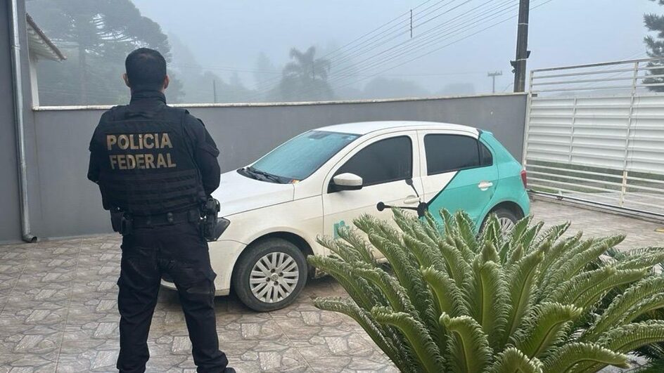 Imagem mostra um policial federal e um carro branco com verde claro no fundo
