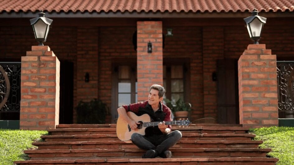 Daniel com violão em escada da entrada da da fazenda de gravação de Viver Sertanejo