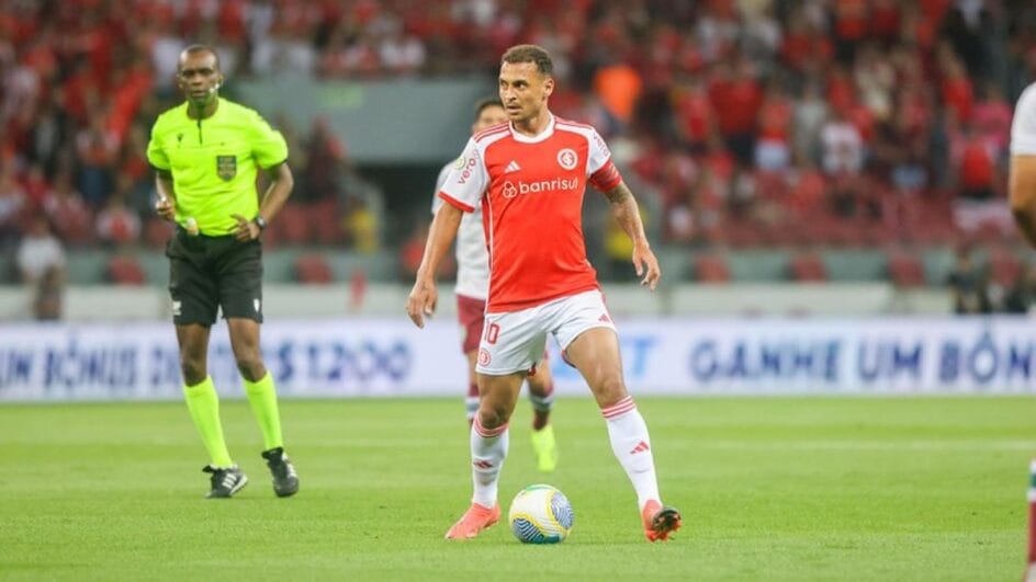 Imagem mostra Alan Patrick com a bola dominada e usando uma camisa vermelha do Internacional