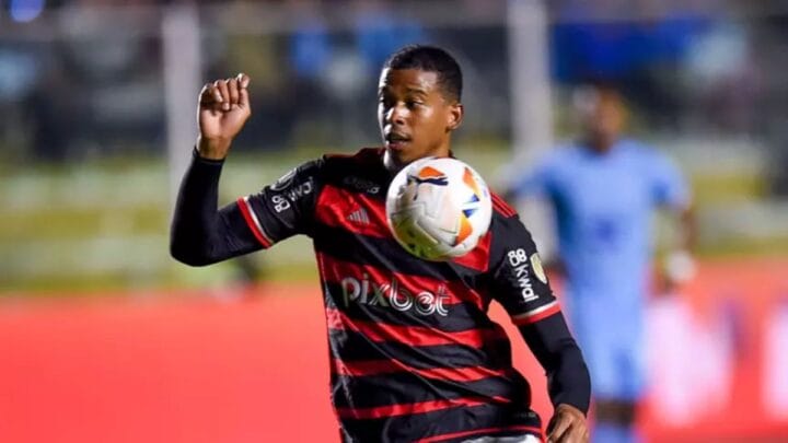 Imagem mostra Carlinhos com a camisa do Flamengo e uma bola em frente ao escudo