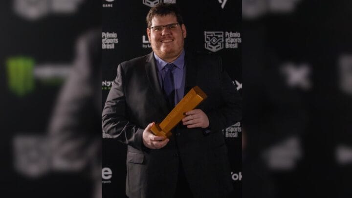 Casimiro aparece vestido em blazer preto e segurando prêmio