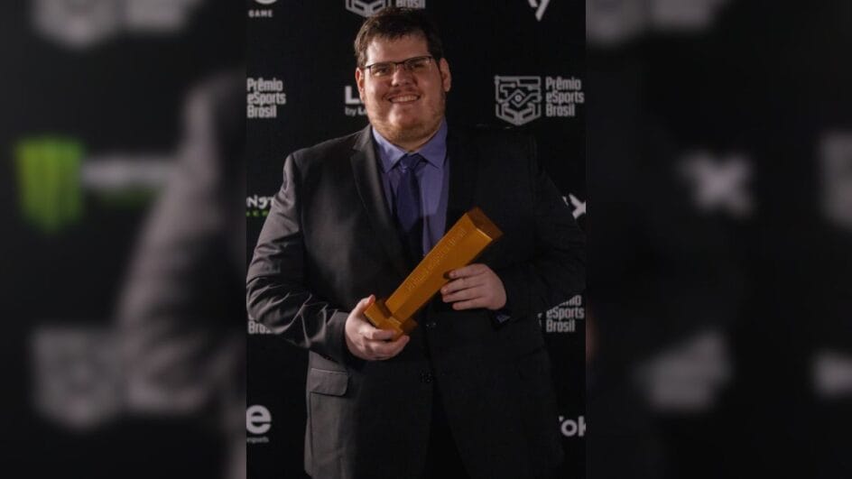 Casimiro aparece vestido em blazer preto e segurando prêmio