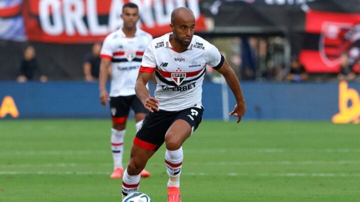 Imagem mostra Lucas com a bola e usando a camisa branca do São Paulo