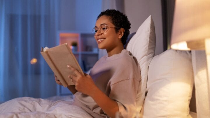 Mulher lendo livro deitada na cama