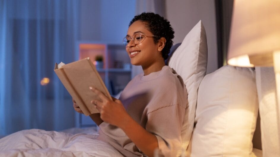 Mulher lendo livro deitada na cama