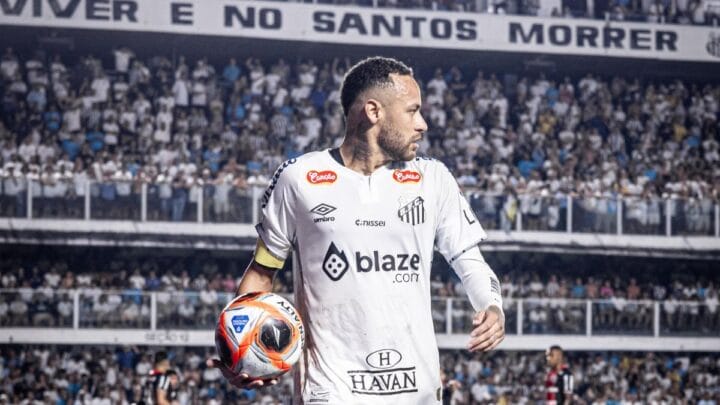 Imagem mostra Neymar com a camisa branca e com a bola na mão olhando para o lado