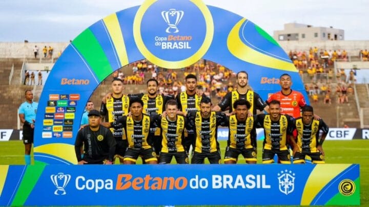 Imagem mostra jogadores do Cascavel com o uniforme listrado em preto e amarelo e a placa da Copa do Brasil