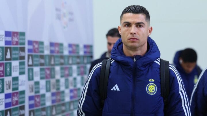 Imagem mostra Cristiano Ronaldo com um casaco azul escuro e o símbolo do Al-Nassr no lado esquerdo e da Adidas no lado direito