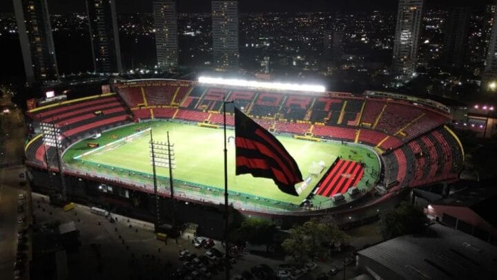 Foto aérea da Ilha do Retiro durante a noite e com a bandeira do clube na frente