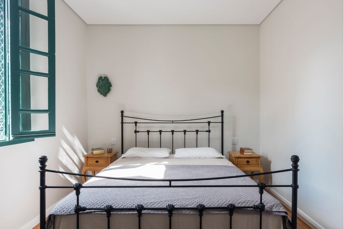 Cabeceira de ferro preta em um quarto com paredes brancas