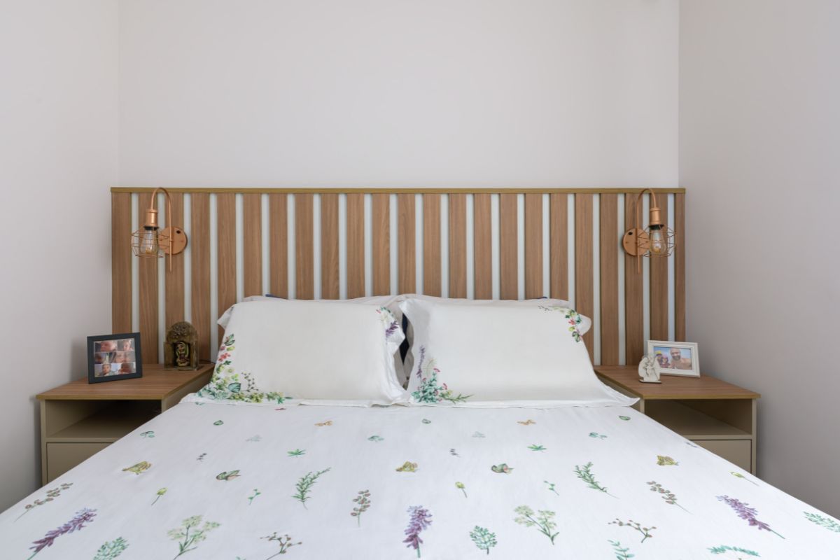 Cabeceira com madeira ripada atrás de uma cama com lençol branco