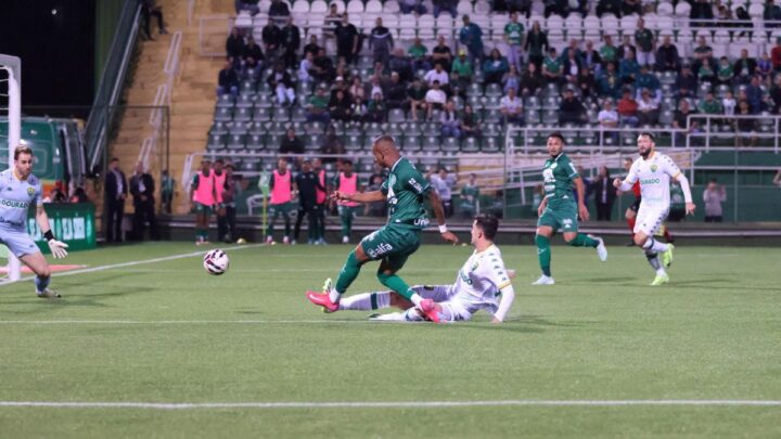 Imagem mostra jogador da Chapecoense chutando e jogador do Cuiabá tentando bloquear