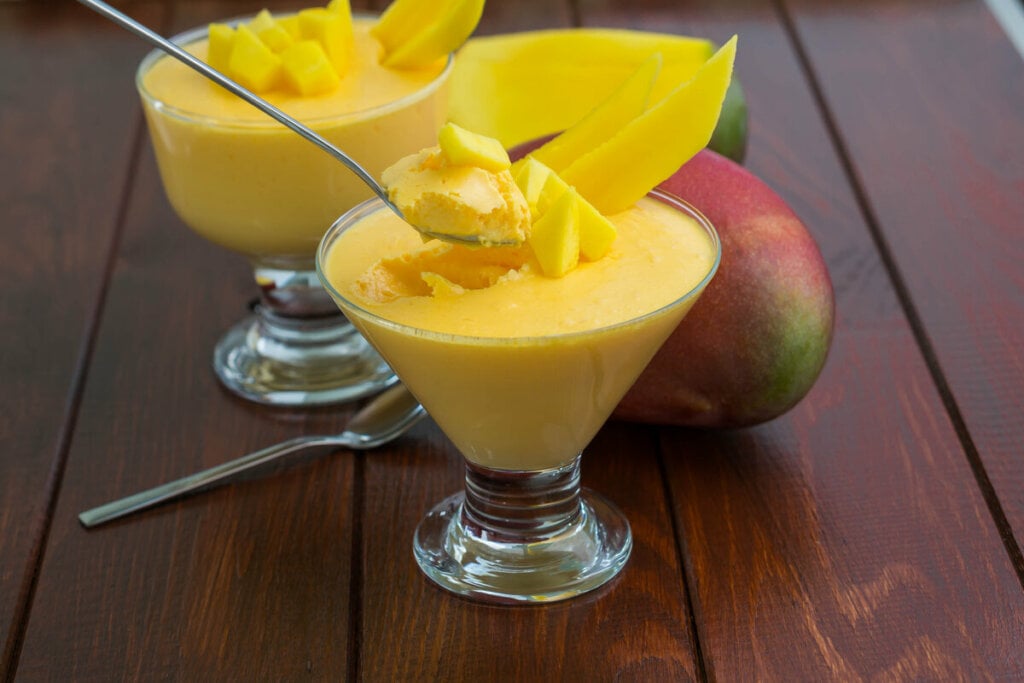 Ta&Atilde;&sect;a de vidro com gelatina cremosa de manga e manga ao fundo