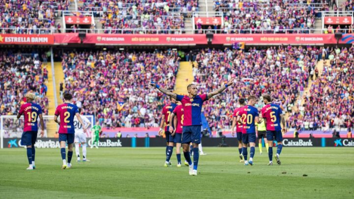Imagem mostra Raphinha de braços abertos e com a camisa do Barcelona