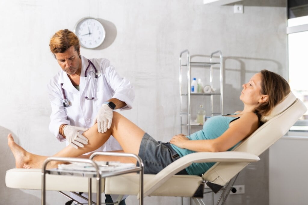 Médica examinando a perna de uma mulher deitada