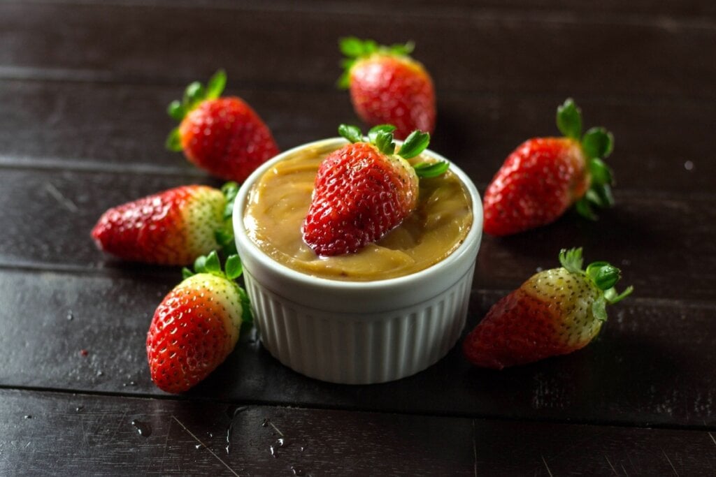Recipiente de vidro branco com doce de leite e morango