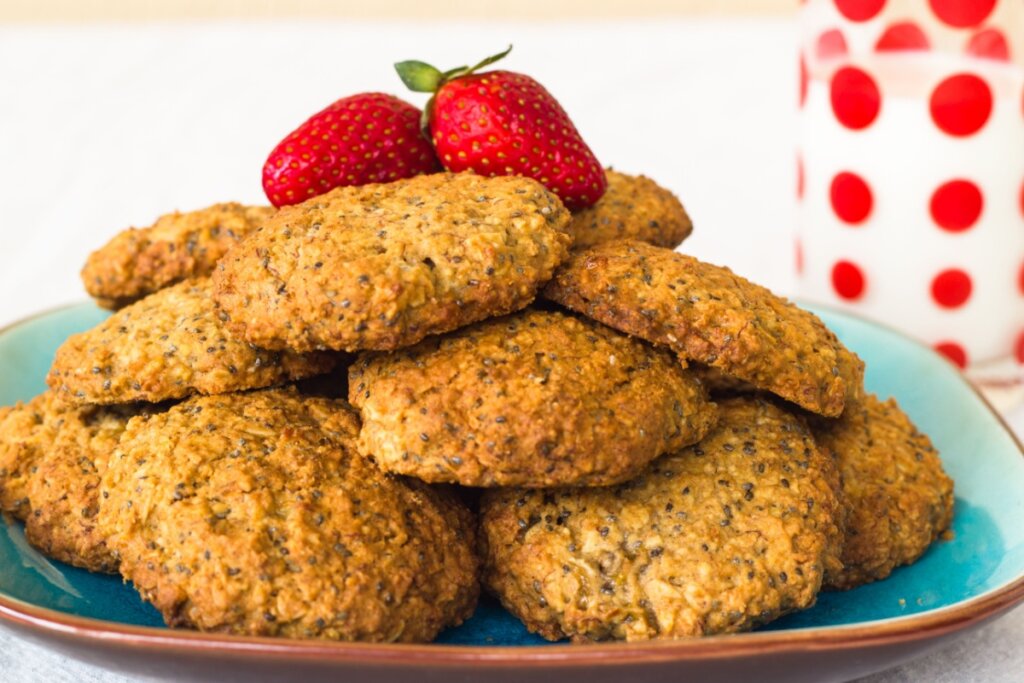 Biscoitos com chia e banana empilhados em cima de um prato verde e decorados com dois morangos