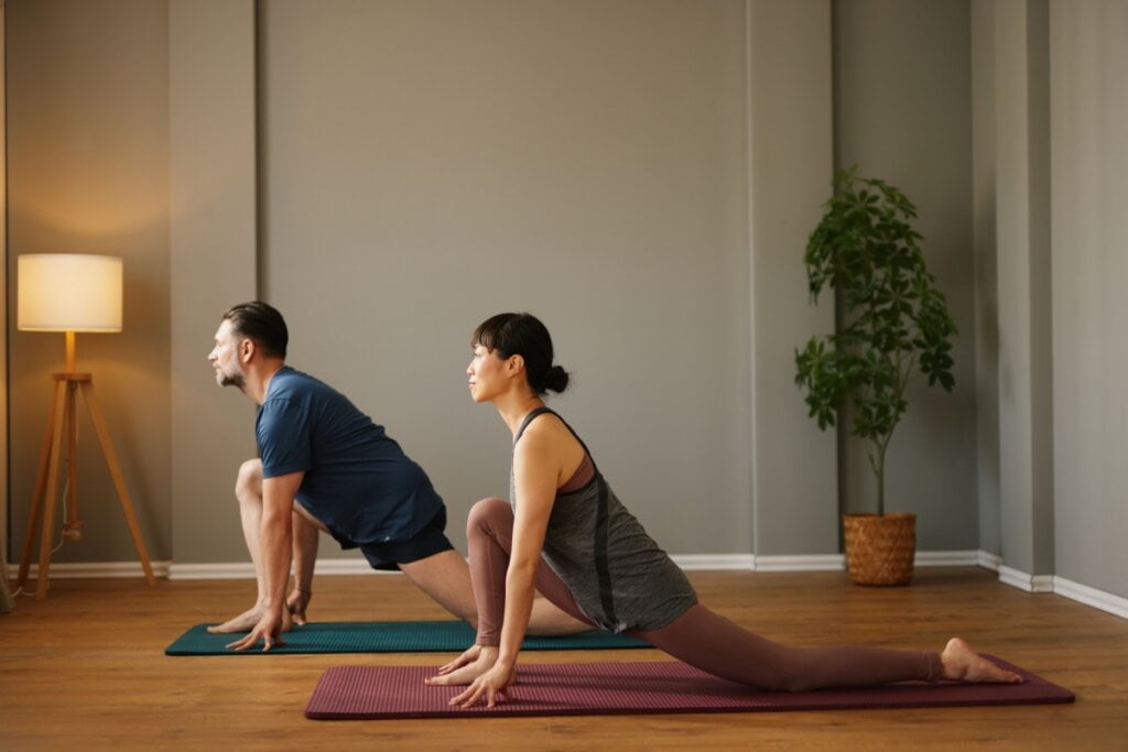 homem e mulher no chão fazendo exercÃcios de yoga em tapete