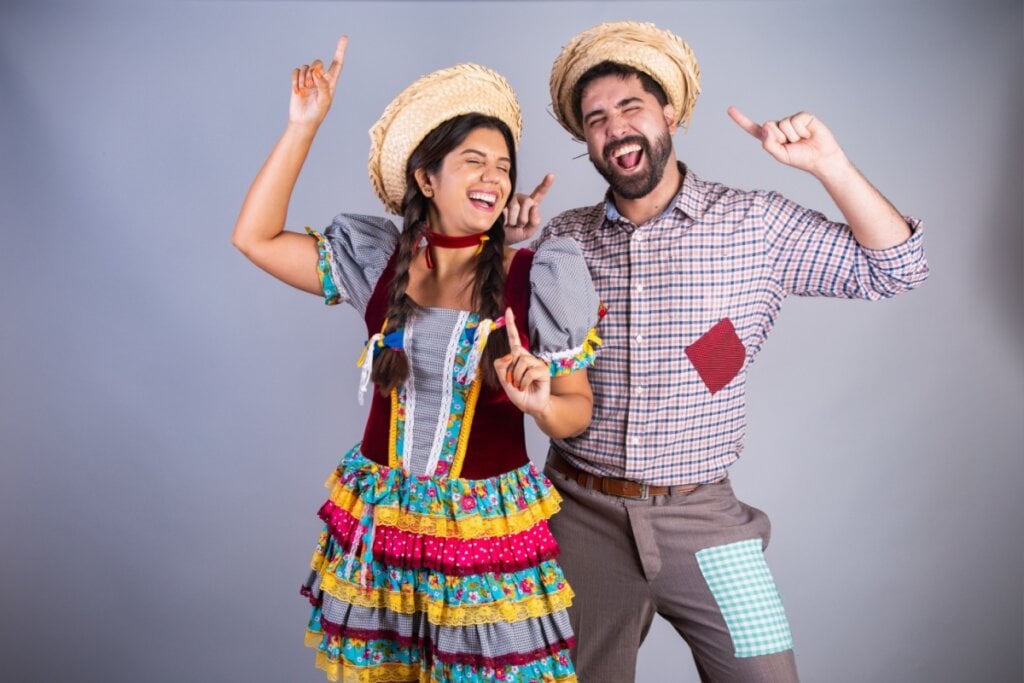 homem e mulher com roupa colorida de festa junina, sorrindo e com os dedos para cima