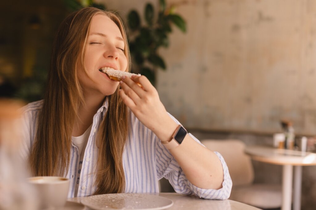 Mulher sentada, comendo pÃ£o com os olhos fechados