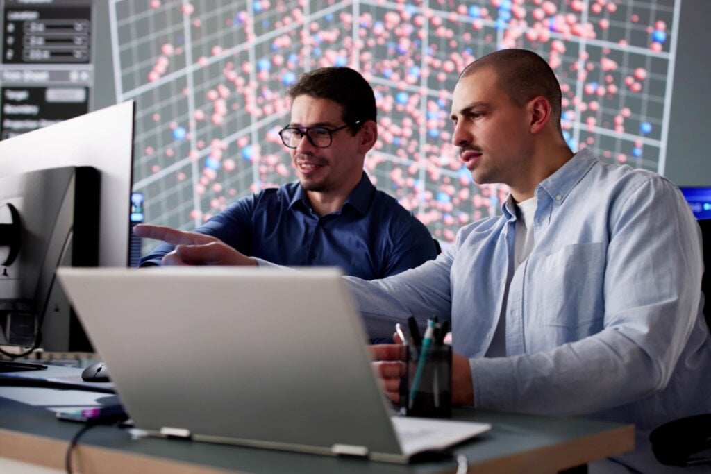 Dois homens trabalhando com computador e notebook