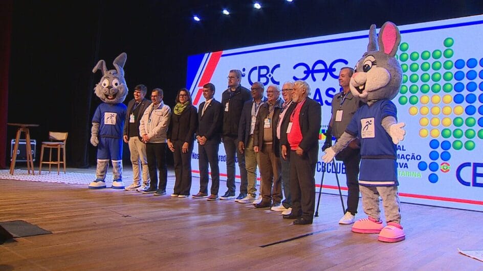 palestrantes reunidos no palco com os mascotes